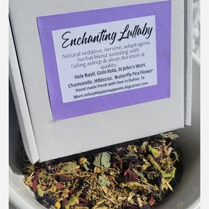May include: A white box with a purple label reading "Enchanting Lullaby" sits above a white bowl filled with dried herbs. The label lists ingredients like Holy Basil, Chamomile, and Butterfly Pea Flower. The text describes the blend as a natural sedative.
