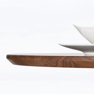 A modern round extendable dining table hand crafted in solid walnut wood.