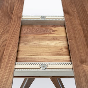 A modern round extendable dining table hand crafted in solid walnut wood.