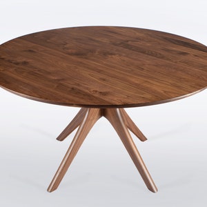 Round dining table handmade in solid walnut wood. This table has a pedestal base with four curved legs connected at the center. The look of the table is midcentury modern, Danish modern and Scandinavian.  The table available in a variety of sizes.