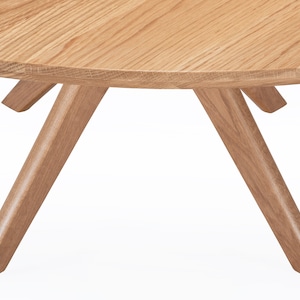 Round dining table handmade in solid white oak wood. This table has a pedestal base with four curved legs connected at the center. The look of the table is midcentury modern, Danish modern and Scandinavian.  The table available in a variety of sizes.