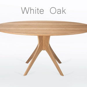 Oval dining table handmade in solid white oak wood. This table has a pedestal base with four curved legs connected at the center. The look of the table is midcentury modern, Danish modern and Scandinavian.  The table available in a variety of sizes.