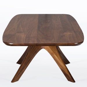 Rectangular coffee table handmade in solid walnut wood. This table has a pedestal base with four curved legs connected at the center. The look of the table is midcentury modern, Danish modern and Scandinavian.  Available in a variety of sizes.