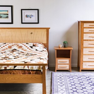 May include: A bedroom set with a wooden bed frame, a nightstand, and a dresser. The bed has a brown and white quilt and a wooden headboard with butterfly inlays. The nightstand has two drawers and the dresser has six drawers. The room has a white wall and a patterned rug.