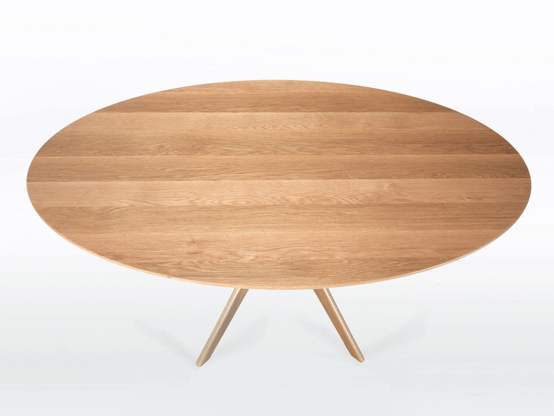 Oval dining table handmade in solid white oak wood. This table has a pedestal base with four curved legs connected at the center. The look of the table is midcentury modern, Danish modern and Scandinavian.  The table available in a variety of sizes.