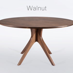 Round dining table handmade in solid walnut wood. This table has a pedestal base with four curved legs connected at the center. The look of the table is midcentury modern, Danish modern and Scandinavian.  The table available in a variety of sizes.