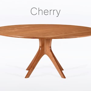 Oval dining table handmade in solid cherry wood. This table has a pedestal base with four curved legs connected at the center. The look of the table is midcentury modern, Danish modern and Scandinavian.  The table available in a variety of sizes.