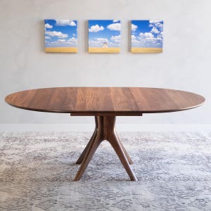 A modern round extendable dining table hand crafted in solid walnut wood.