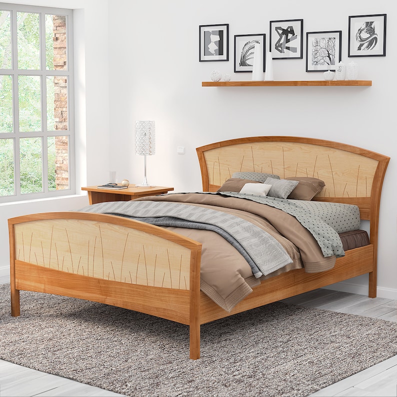 This is a handmade wooden bed with a curved headboard and footboard.  The headboard and footboard are inlaid with curved wood pieces that look like river rushes.  The bed is made with cherry and curly maple wood.