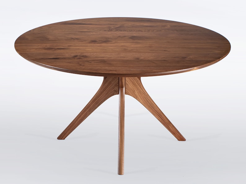 Round dining table handmade in solid walnut wood. This table has a pedestal base with four curved legs connected at the center. The look of the table is midcentury modern, Danish modern and Scandinavian.  The table available in a variety of sizes.