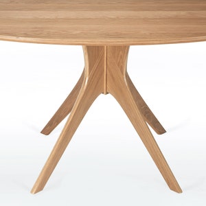 Oval dining table handmade in solid white oak wood. This table has a pedestal base with four curved legs connected at the center. The look of the table is midcentury modern, Danish modern and Scandinavian.  The table available in a variety of sizes.