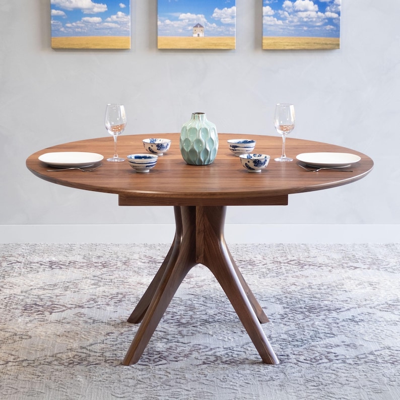 A modern round extendable dining table hand crafted in solid walnut wood.