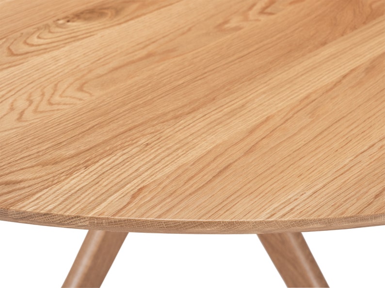 Round dining table handmade in solid white oak wood. This table has a pedestal base with four curved legs connected at the center. The look of the table is midcentury modern, Danish modern and Scandinavian.  The table available in a variety of sizes.