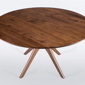 Round dining table handmade in solid walnut wood. This table has a pedestal base with four curved legs connected at the center. The look of the table is midcentury modern, Danish modern and Scandinavian.  The table available in a variety of sizes.