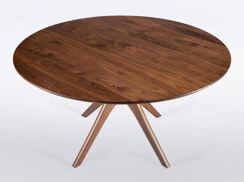 Round dining table handmade in solid walnut wood. This table has a pedestal base with four curved legs connected at the center. The look of the table is midcentury modern, Danish modern and Scandinavian.  The table available in a variety of sizes.