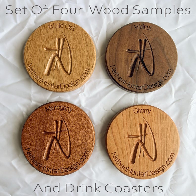 May include: Set of four round wooden coasters featuring different wood types: white oak, walnut, mahogany, and cherry. Each coaster has a carved design and the text "NathanHunterDesign.com".