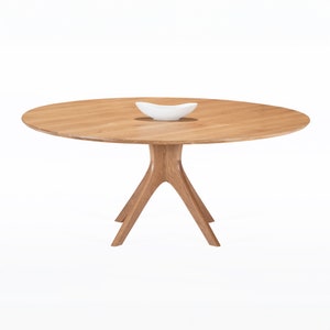 Round dining table handmade in solid white oak wood. This table has a pedestal base with four curved legs connected at the center. The look of the table is midcentury modern, Danish modern and Scandinavian.  The table available in a variety of sizes.