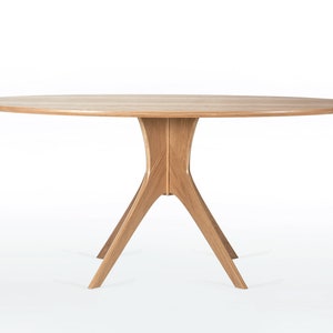 Oval dining table handmade in solid white oak wood. This table has a pedestal base with four curved legs connected at the center. The look of the table is midcentury modern, Danish modern and Scandinavian.  The table available in a variety of sizes.