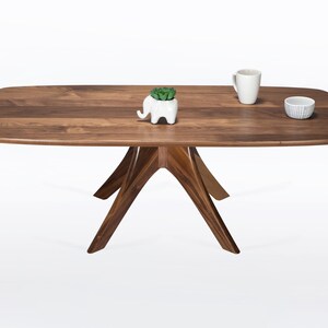 Rectangular coffee table handmade in solid walnut wood. This table has a pedestal base with four curved legs connected at the center. The look of the table is midcentury modern, Danish modern and Scandinavian.  Available in a variety of sizes.