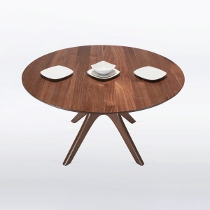A modern round extendable dining table hand crafted in solid walnut wood.