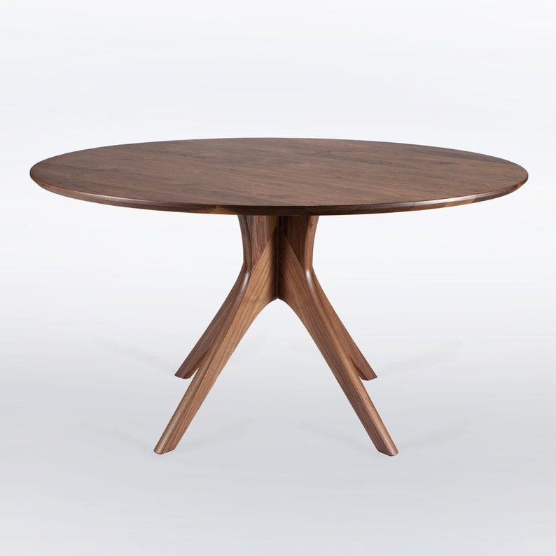 Modern round dining table in solid walnut wood with sleek finish, featuring an elegant four-legged pedestal base design. Ideal for contemporary dining room settings.