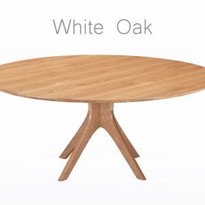 Round dining table handmade in solid white oak wood. This table has a pedestal base with four curved legs connected at the center. The look of the table is midcentury modern, Danish modern and Scandinavian.  The table available in a variety of sizes.