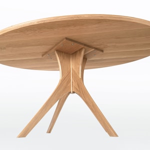 Oval dining table handmade in solid white oak wood. This table has a pedestal base with four curved legs connected at the center. The look of the table is midcentury modern, Danish modern and Scandinavian.  The table available in a variety of sizes.