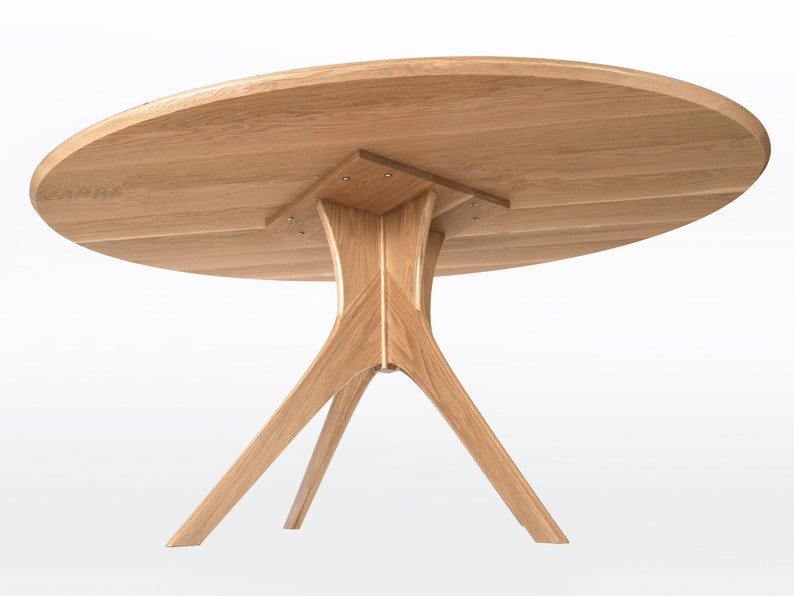 Oval dining table handmade in solid white oak wood. This table has a pedestal base with four curved legs connected at the center. The look of the table is midcentury modern, Danish modern and Scandinavian.  The table available in a variety of sizes.