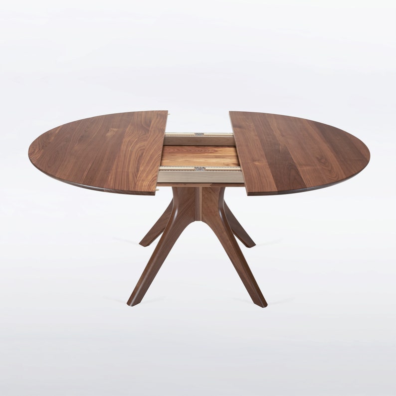 A modern round extendable dining table hand crafted in solid walnut wood.