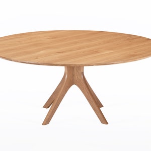 Round dining table handmade in solid white oak wood. This table has a pedestal base with four curved legs connected at the center. The look of the table is midcentury modern, Danish modern and Scandinavian.  The table available in a variety of sizes.