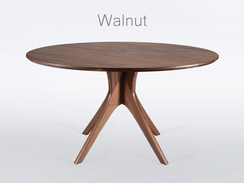 Oval dining table handmade in solid walnut wood. This table has a pedestal base with four curved legs connected at the center. The look of the table is midcentury modern, Danish modern and Scandinavian.  The table available in a variety of sizes.