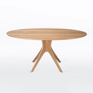 Oval dining table handmade in solid white oak wood. This table has a pedestal base with four curved legs connected at the center. The look of the table is midcentury modern, Danish modern and Scandinavian.  The table available in a variety of sizes.