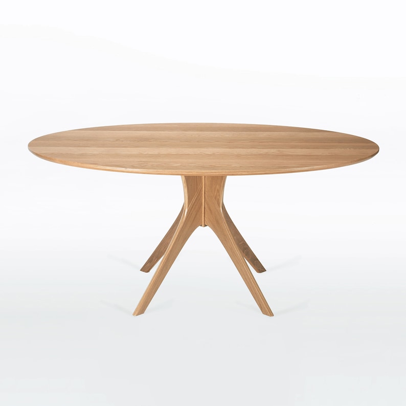 Oval dining table handmade in solid white oak wood. This table has a pedestal base with four curved legs connected at the center. The look of the table is midcentury modern, Danish modern and Scandinavian.  The table available in a variety of sizes.