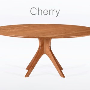 Round dining table handmade in solid cherry wood. This table has a pedestal base with four curved legs connected at the center. The look of the table is midcentury modern, Danish modern and Scandinavian.  The table available in a variety of sizes.