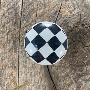 May include: Black and white checkered ceramic knob. The knob is round and has a glossy finish.