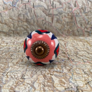 以下が含まれることがあります： ピンク、白、青、緑のセラミックノブで、中央に金色の金属があります。ノブは花柄です。