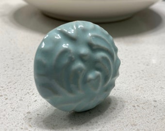 May include: A light blue ceramic knob with a swirl design.