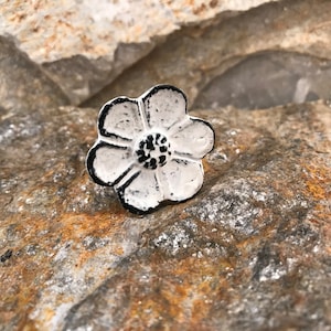 May include: White cast iron flower shaped cabinet knob with a black centre.