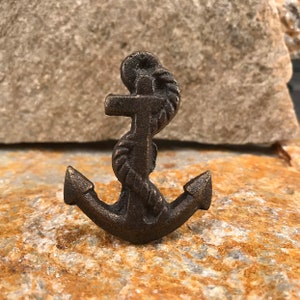 May include: A small, cast iron anchor with a rope design. The anchor is a dark brown colour and has a rustic finish.