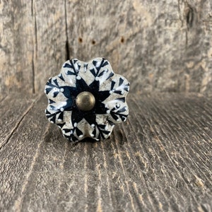 May include: A white ceramic knob with a black and white floral design. The knob has a brass center.