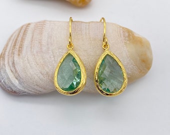 Puede incluir: Un par de pendientes de gota de oro con piedras facetadas de color verde claro.