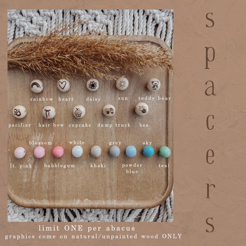 May include: Wooden beads with engraved designs and various colors, including light pink, bubblegum, white, grey, sky, and teal. The beads feature images of a rainbow, heart, daisy, sun, teddy bear, pacifier, hair bow, cupcake, dump truck, and bee.