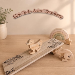 May include: A wooden animal race ramp toy featuring the text Click Clack - Animal Race Ramp. The ramp is decorated with black line art of flowers and rabbits. A wooden duck figure sits on the ramp, and a wooden rabbit figure stands nearby.
