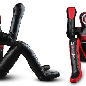 May include: A black and red training dummy with a white circle on the chest. The dummy is in a seated position with its arms raised. The text "DAAN" is printed on the left leg and "MMA" is printed on the right leg.