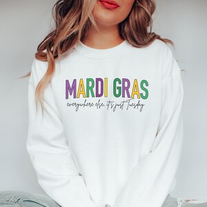 May include: White sweatshirt with the text "Mardi Gras" in purple, green, and yellow letters. The text "everywhere else, it's just Tuesday" is written in cursive below the main text.