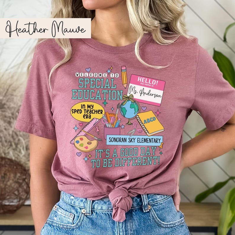 K&ouml;nnte beinhalten: Rosa T-Shirt mit einem Grafikdesign mit der Aufschrift "Willkommen in der Sonderp&auml;dagogik", einem Globus, einem Bleistift, einem Lineal, einer Farbpalette und dem Text "Es ist ein guter Tag, um anders zu sein!"