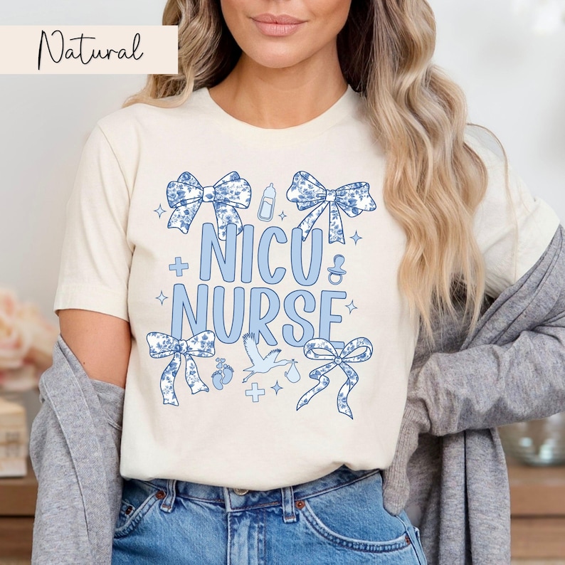 May include: A white t-shirt with a blue design that says "NICU NURSE" with blue bows, a baby bottle, a stork, and other baby-related icons.