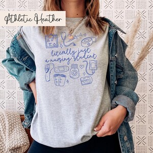 May include: A heather gray t-shirt with a blue graphic of medical supplies and the text "literally just a nursing student".