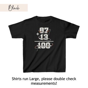 May include: Black t-shirt with a white graphic of a math equation: 87 + 13 = 100. The numbers are surrounded by colorful beads.
