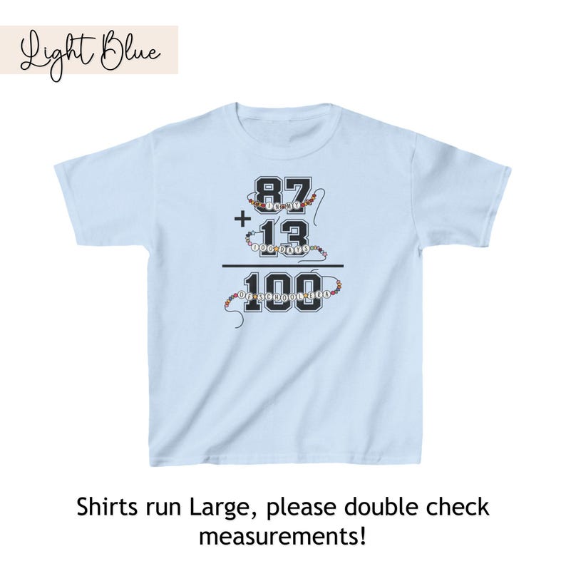 May include: Light blue t-shirt with a math equation printed on the front. The equation is 87 + 13 = 100. The numbers are made of colorful beads.